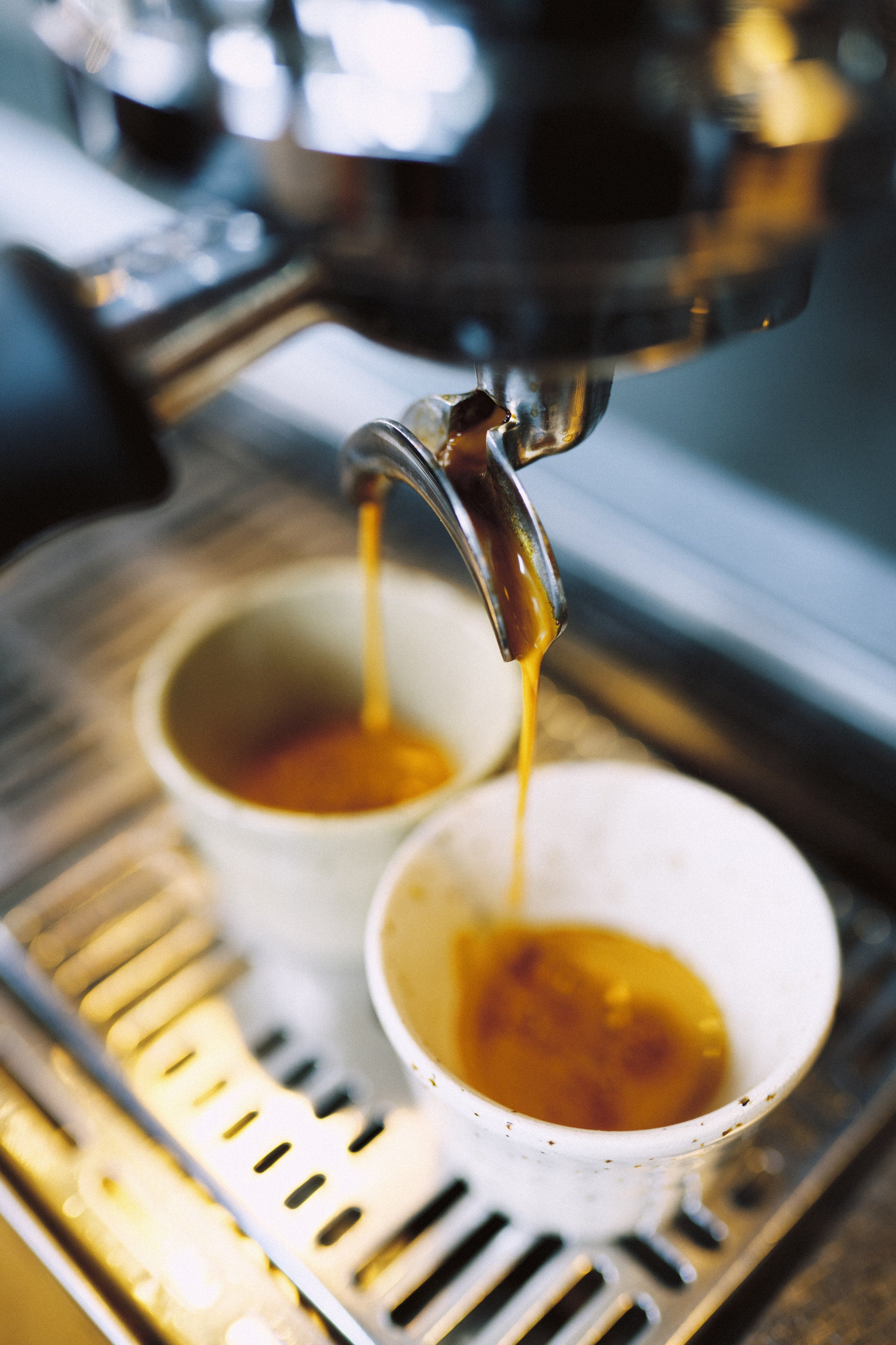 Dos tazas de café bajo la máquina de espresso